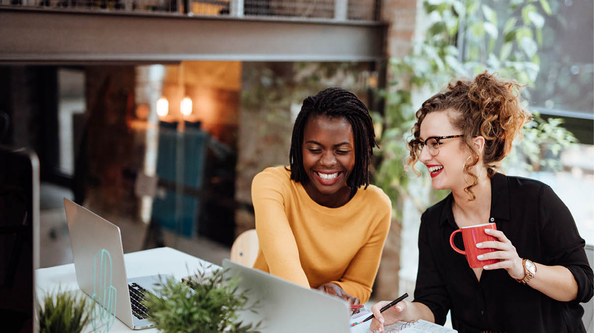 Two Businesswomen Working On Computer In Office