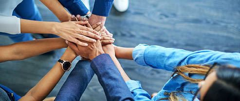High angle shot of a group of colleagues joining their hands together in unity