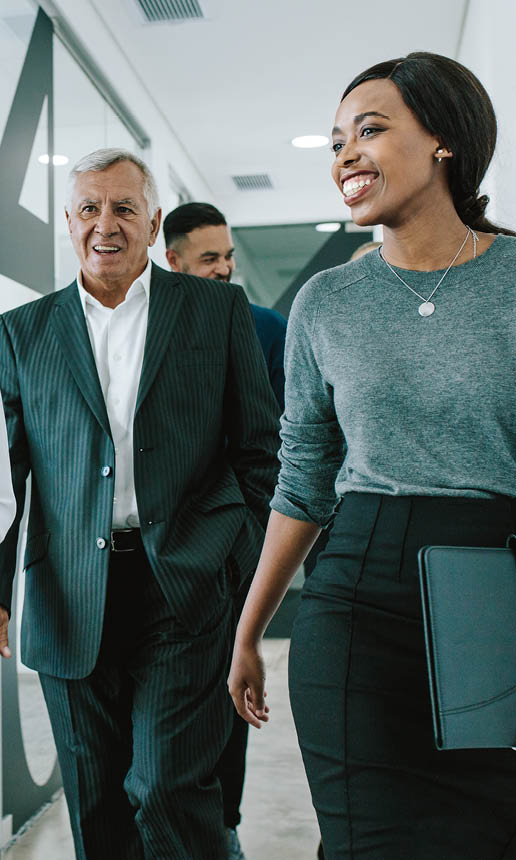 Diverse group of business people walking through office corridor   Team of corporate professionals walking and talking in modern office hallway 