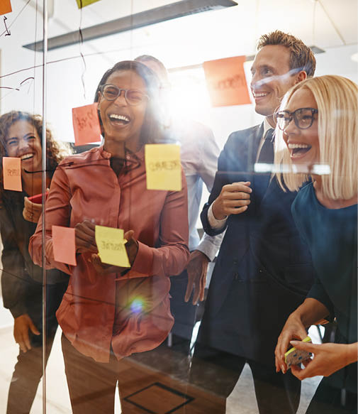 Laughing group of diverse businesspeople having a brainstorming session together with sticky notes in an office